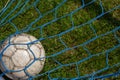 old soccer ball in the net on the background of grass soccer field. Summer sunny day Royalty Free Stock Photo