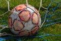 Old soccer ball in the net on the background of grass soccer field. Summer sunny day Royalty Free Stock Photo