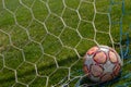 Old soccer ball in the net on the background of grass soccer field. Summer sunny day Royalty Free Stock Photo