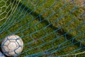 Old soccer ball in the net on the background of grass soccer field. Summer sunny day Royalty Free Stock Photo