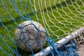 old soccer ball in the net on the background of grass soccer field. Summer sunny day Royalty Free Stock Photo