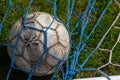 Old soccer ball in the net on the background of grass soccer field. Summer sunny day Royalty Free Stock Photo