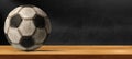 Old Soccer Ball on Wooden Table with empty Blackboard on background Royalty Free Stock Photo