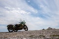 An old Soviet motorcycle with a sidecar stands against the sky with clouds on the stones. Royalty Free Stock Photo