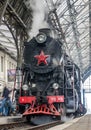 Old Soviet vintage black retro train with a red star at the railway station in Lviv produces steam from the pipes and the passeng Royalty Free Stock Photo