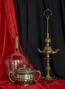 Old Spanish Oil Lamp Glass Demijohn and Silver sugar Bowl Red and Black Background Still Life