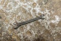 Old spanner on rumpled shabby metal, close-up abstract background