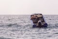 An old speedboat slowly sails towards the horizon, rising on a wave Royalty Free Stock Photo