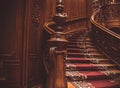 Old spiral wooden staircase with vintage railing indoors, covered with a carpet. luxury carved wood interior in the palace. rare