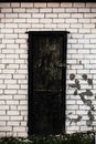 Old spooky wooden door with a lock in white brick wall Royalty Free Stock Photo