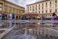 Old square in Florence with carousel and people and tourists haveing fun reflections in puddle