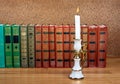 Old stack of books with candlestick and burning candle Royalty Free Stock Photo