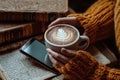 An old stack of books is topped with a stack of hands holding a coffee cup and phone. Royalty Free Stock Photo