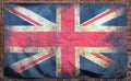 Old stained dirty union jack british flag with dark crumpled edges on a brick wall background Royalty Free Stock Photo