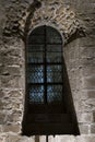 Old stained-glass window casting blue light inside a medieval stone chapel. Royalty Free Stock Photo