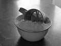 Old stainless steel cup flour sifter in a white enamel bowl with wheat flour on an old scratched table Royalty Free Stock Photo