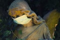 Old statue angel with a medical mask covid-19 concept, danger, death Royalty Free Stock Photo