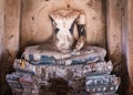 Old statue of Buddha, headless and armless. Flower garland as offering next to left foot. Destroyed and broken sculpture, ancient