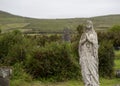 Old statue of Mary or angel in cemetary, covered in moss, praying