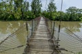 Old steel cable and wooden footbridge across river. Wooden suspension bridge.