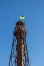 Old steel lighthouse with Ukrainian national flag on top. Abandoned lighthouse on island, Ukraine. Patriotism concept.