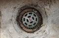 Old steel round storm drain grate on the main hole drains the water. A dirty rusted metal grate to filter debris to prevent
