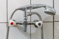 Old steel shower faucet at white vintage tile background