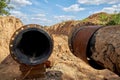 An old steel water pipe with a welded flange lies next to a new plastic pipe installed to connect the water Royalty Free Stock Photo