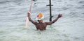 Old stilt fisherman with his fishing rod and empty bag in hands and swims towards his bamboo pole in the Mirissa beach shore,