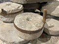 Old stone agricultural millstones for grinding grains into flour. Ancient primitive hand tool of circular shape with an iron hoop