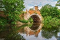 Old stone arch bridge over river with reflection in the water, summer day Royalty Free Stock Photo