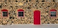 Old Stone Barn with Bright Red Door and Three Windows Royalty Free Stock Photo