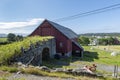 Old stone bridge connecting to a red barn surrounded by greenery and short trees in Alesund, Norway Royalty Free Stock Photo