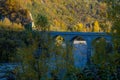 Old stone bridge over the mountain river across autumn forest, hills, and sunset sky. Natural background. Travel, movement, archit Royalty Free Stock Photo