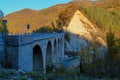 Old stone bridge over the mountain river across autumn forest, hills, and sunset sky. Natural background. Travel, movement, archit Royalty Free Stock Photo