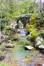 An old stone bridge over some small waterfalls and mossy rocks. Royalty Free Stock Photo