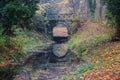 The old stone bridge of the stream in the deciduous forest, beautiful reflection in the calm stream water Royalty Free Stock Photo