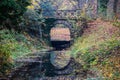 The old stone bridge of the stream in the deciduous forest, beautiful reflection in the calm stream water Royalty Free Stock Photo