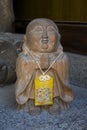 Old stone buddha statue with a Japanese amulet called omamori at the Shofukuji temple grounds