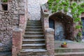 Old stone building with brick walled steps leading upwards beside arched niche with wrought iron table and chairs Royalty Free Stock Photo