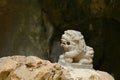 An old stone Chinese guardian lion statue in front of the mystery cave entrance