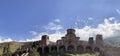 Old stone church on background of blue sky with white clouds. Architecture of monastery from uneven different ancient