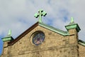 Old stone church with copper cross atop it