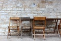 Old stone exterior wall of building with rows of mismatched chairs set against it