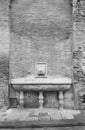 An old stone fountain on the side of a wall in the town of San Miniato in Tuscany, shot with black and white analogue film Royalty Free Stock Photo