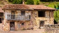Old stone house with balcony, red roof, wooden doors. Carmona, Cantabria, Spain