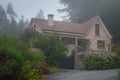 Old stone house with beautiful garden in morning fog. Rural cottage in village in forest. Cozy residence with trees and flowers. Royalty Free Stock Photo