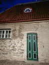 An old stone house with a green door, white windows and a tiled roof on one of the narrow streets of Old Tallinn against the blue Royalty Free Stock Photo