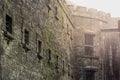 Old stone jail wall with small windows with metal bars. Sun flare. Law correction facility with hard living conditions. Cork Gaol