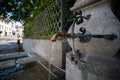 Old stone and metal public drinking water fountain in a city in Switzerland, Europe. Daytime, wide angle, no peop